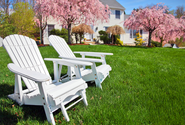 white muskoka chairs in front of luxury home in summer