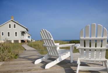 two white Muskoka chairs at a cottage looking out over Lake Huron