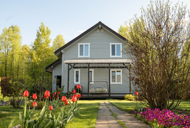 Modern country house with spring garden and red tulips in sunny yard