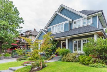 large light blue house with luscious greenery